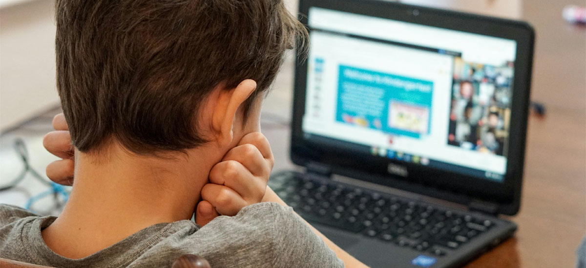 The back of a kid's head as he looks at a computer.