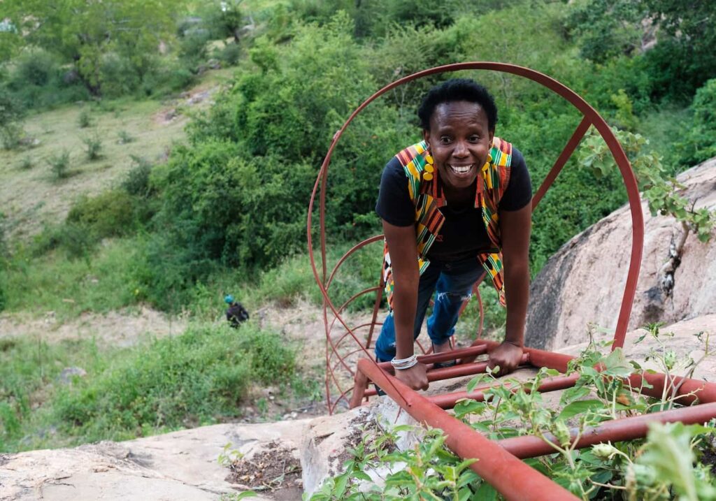 A woman ascends a metal ladder positioned on a rocky hill